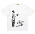 A white short-sleeved graphic tee with a black and white illustration of a basketball player and the text 'THE ROCK PLAN' on the front.